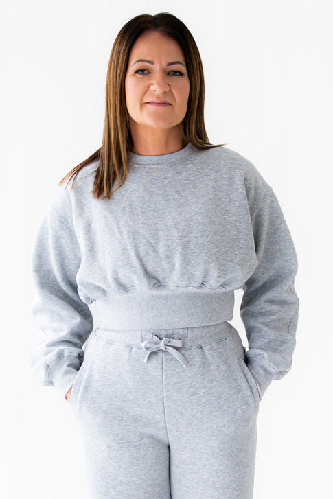 Woman wearing a gray sweatshirt and pants set on a white background