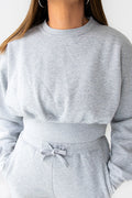 Gray sweatshirt and pants set worn by a person against a white background