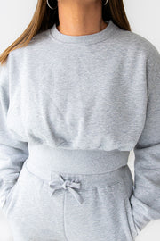 Gray sweatshirt and pants set worn by a person against a white background