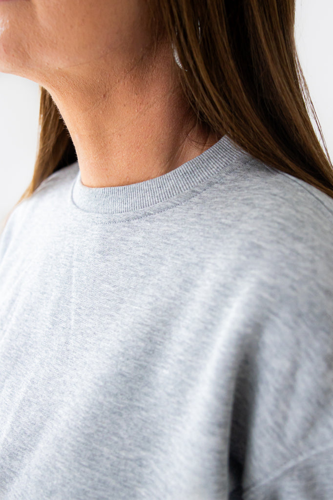 Gray sweatshirt worn by a person with a neutral background
